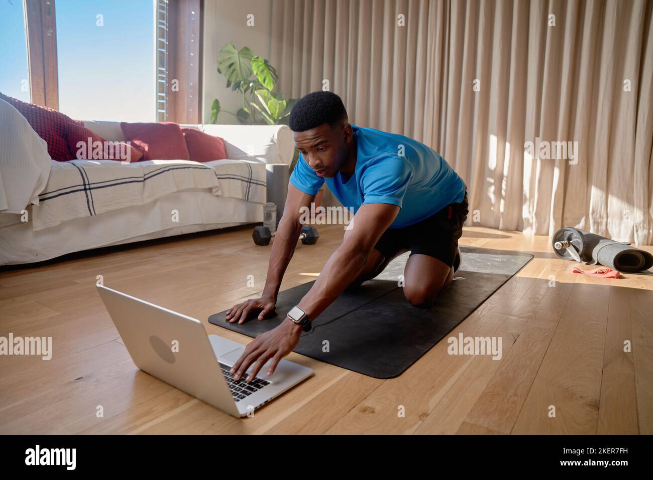 Jeune athlète afro-américain noir s'entraîner à la maison à l'aide d'un ordinateur portable, faisant un cours d'exercice en ligne. Maintien de la forme et de la santé Banque D'Images