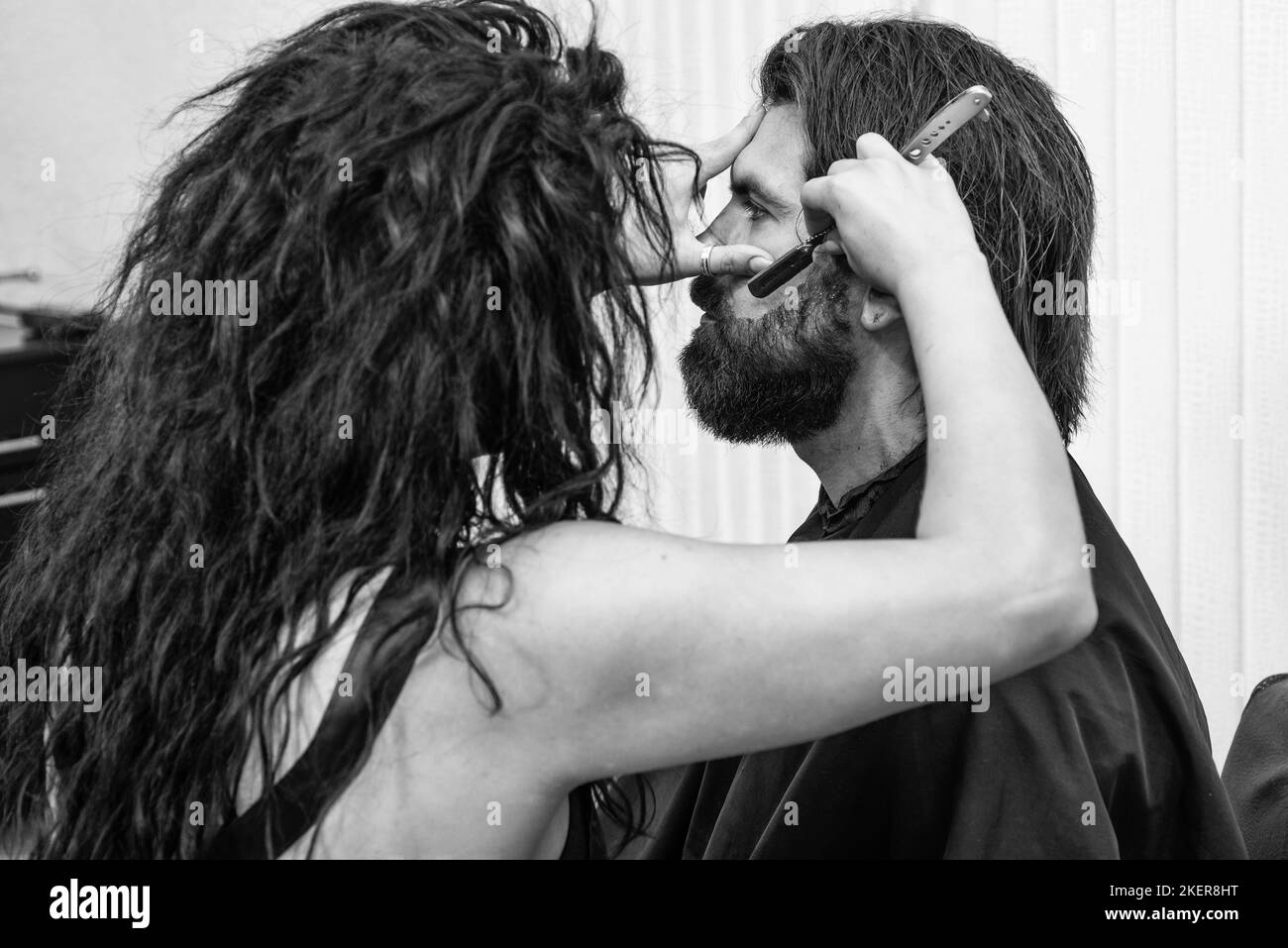 un boxeur mûr avec barbe et moustache se charge de ses cheveux dans un salon de coiffure, le toilettage de la barbe Banque D'Images