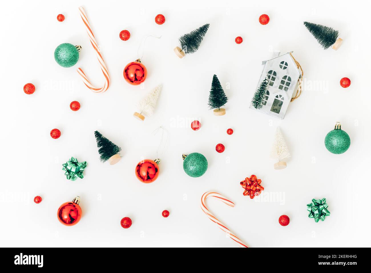 Décorations de Noël, concept de vacances. Maison miniature, sapins, boules et bonbons sur fond blanc, vue de dessus Banque D'Images