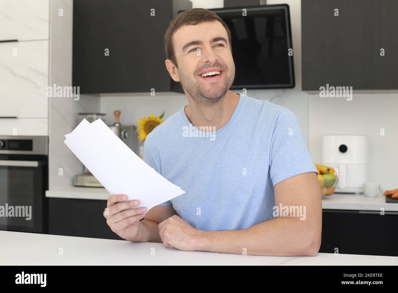 Homme satisfait regardant quelques documents dans la cuisine Banque D'Images