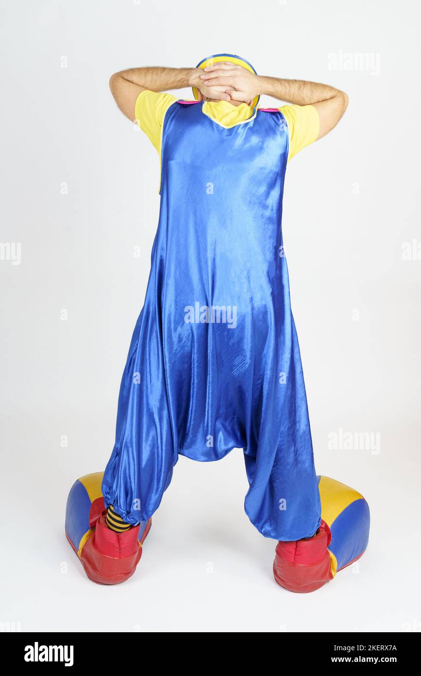 Concept de vacances. Le clown se tient avec son dos à la caméra, tient ses mains derrière sa tête - arrêté Banque D'Images