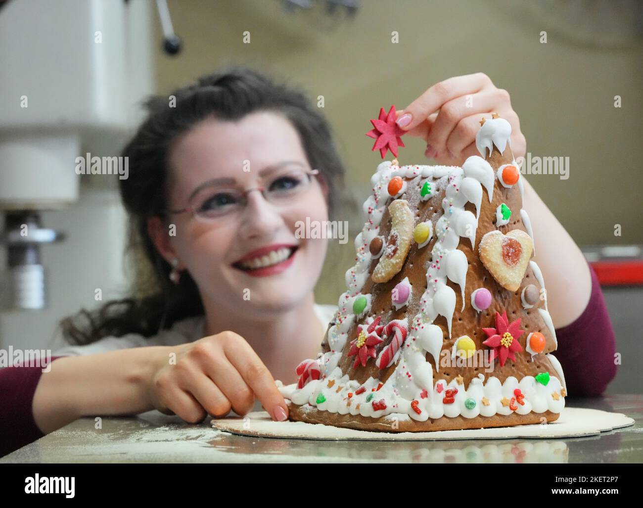 14 novembre 2022, Brandebourg, Oberkrämer/OT Schwante: Lors d'un événement de presse à la boulangerie et confiserie Plentz, Patricia place une étoile de sucre rouge sur une maison de pain d'épice presque finie de sa propre production. La maison de pain d'épice peut être achetée dans le magasin, mais aussi comme un kit avec des instructions détaillées dans la boutique en ligne. La construction de la maison de pain d'épice est également disponible sur 19.11.2022 pour la "fin de la saison au four à bois" en plus des séminaires de cuisson de stollen et de la coupe traditionnelle du compteur stollen. En même temps, les boîtes remplies peuvent à nouveau b Banque D'Images