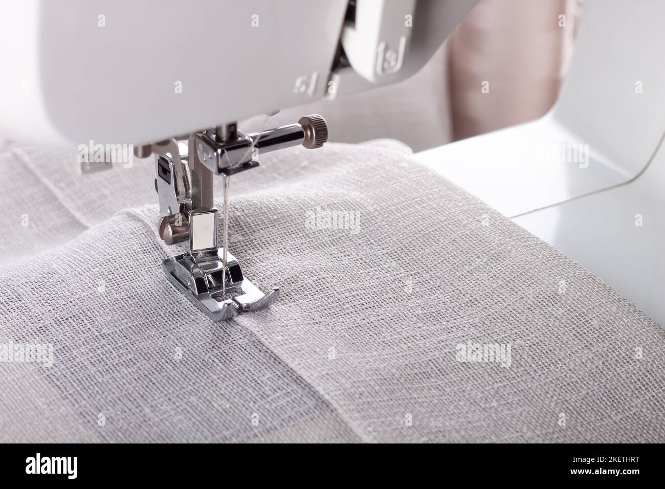 Machine à coudre moderne presser le pied avec le tissu et le fil de lin, gros plan, espace de copie. Processus de couture vêtements, rideaux, tissus d'ameublement. Affaires, passe-temps, h Banque D'Images