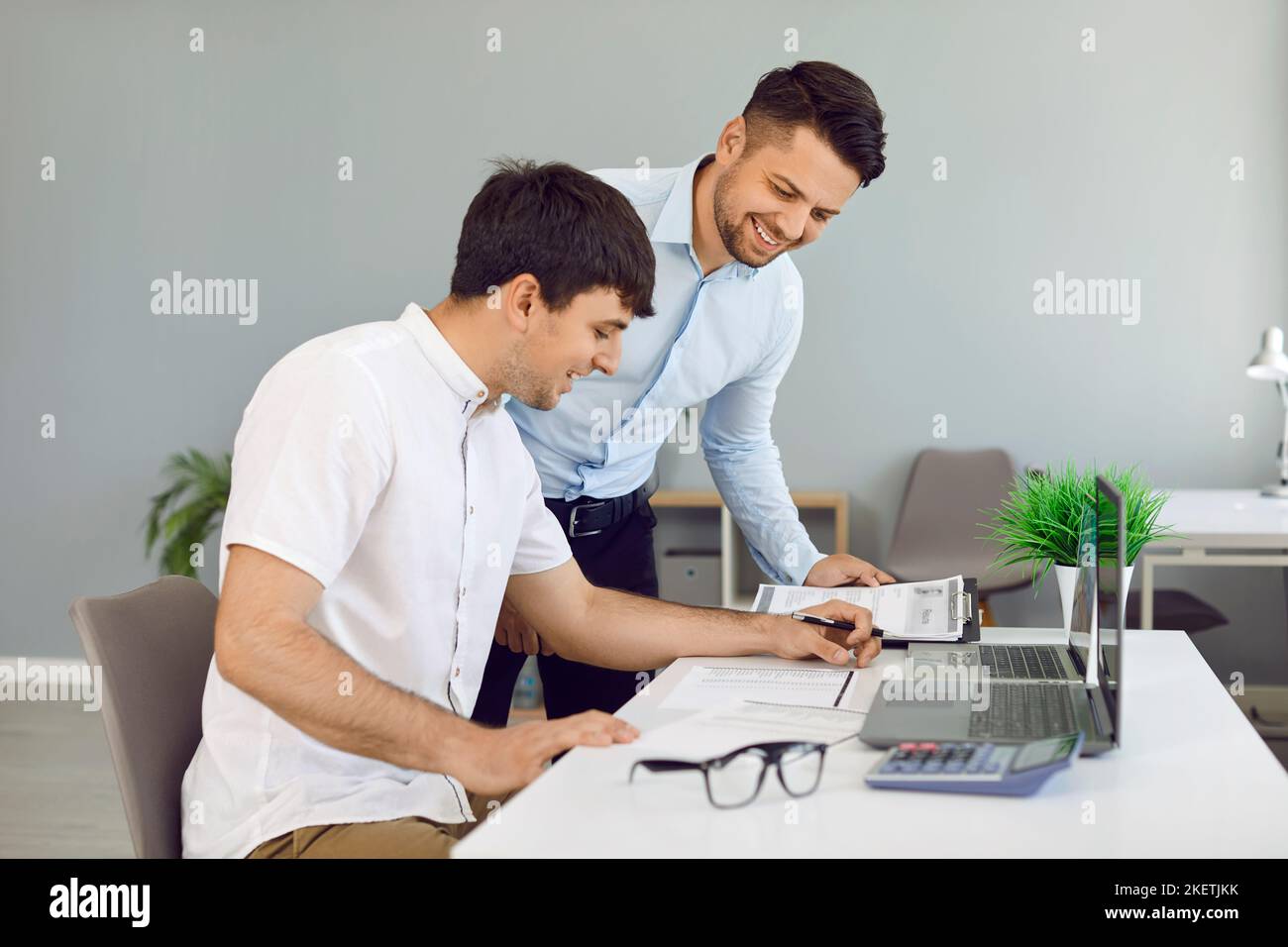 Deux jeunes hommes heureux travaillant au bureau et regardant des documents d'affaires Banque D'Images