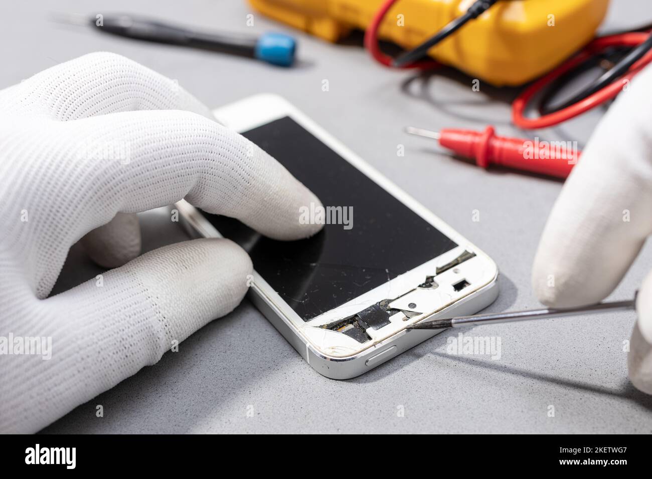 Le technicien travaille sur un smartphone cassé pour réparer ou remplacer une pièce neuve sur le bureau. Gros plan Banque D'Images