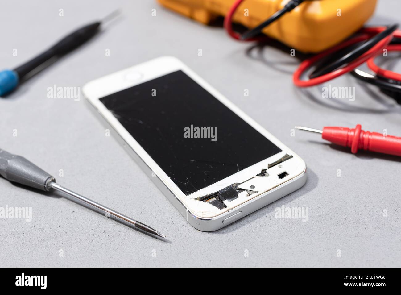Gros plan du smartphone avec écran cassé sur l'établi du magasin électronique. Réparation du concept de téléphone portable endommagé Banque D'Images