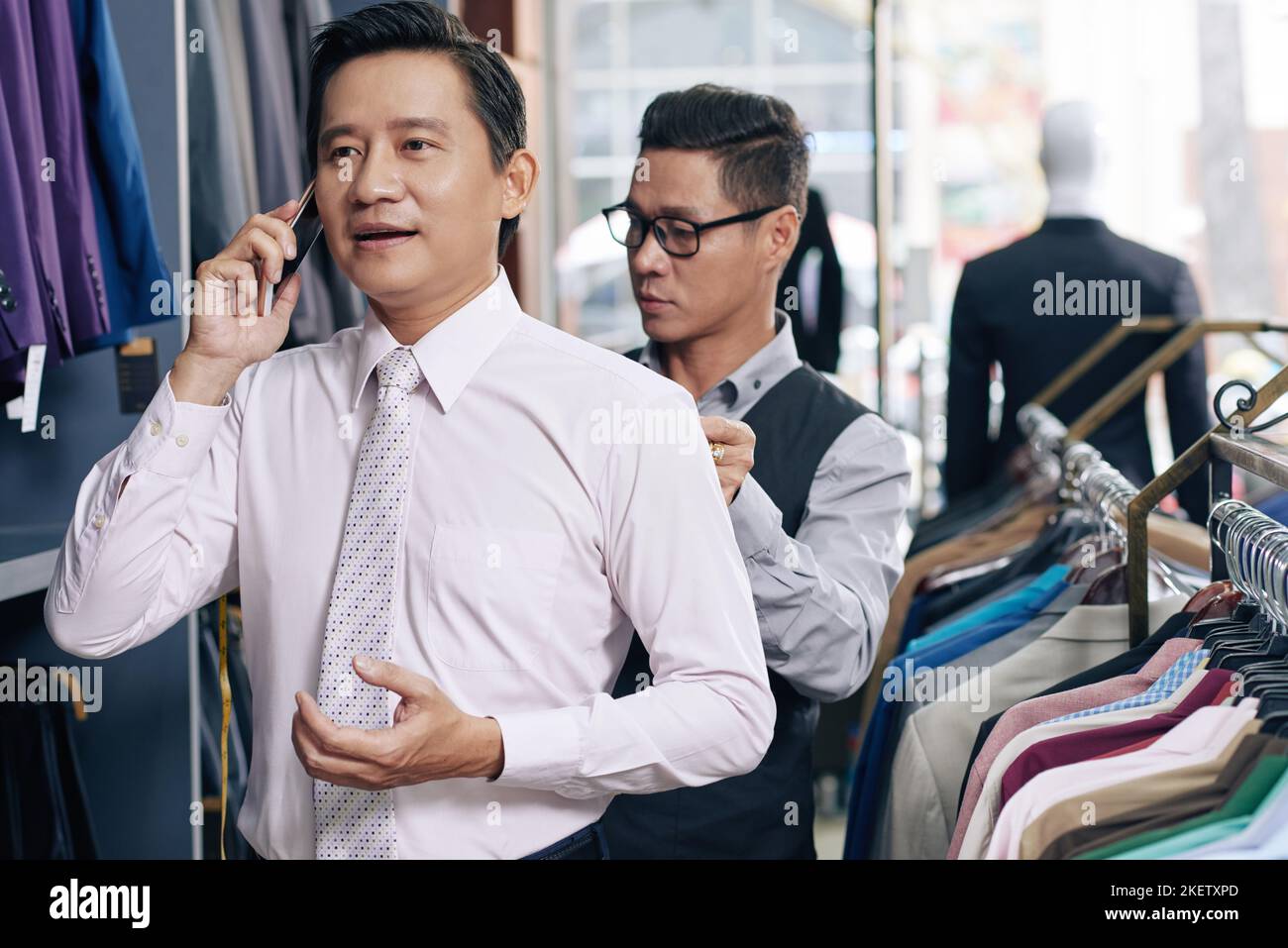 Un homme d'affaires vietnamien mature qui appelle au téléphone quand il a ses shouders déguisés pour le costume Banque D'Images