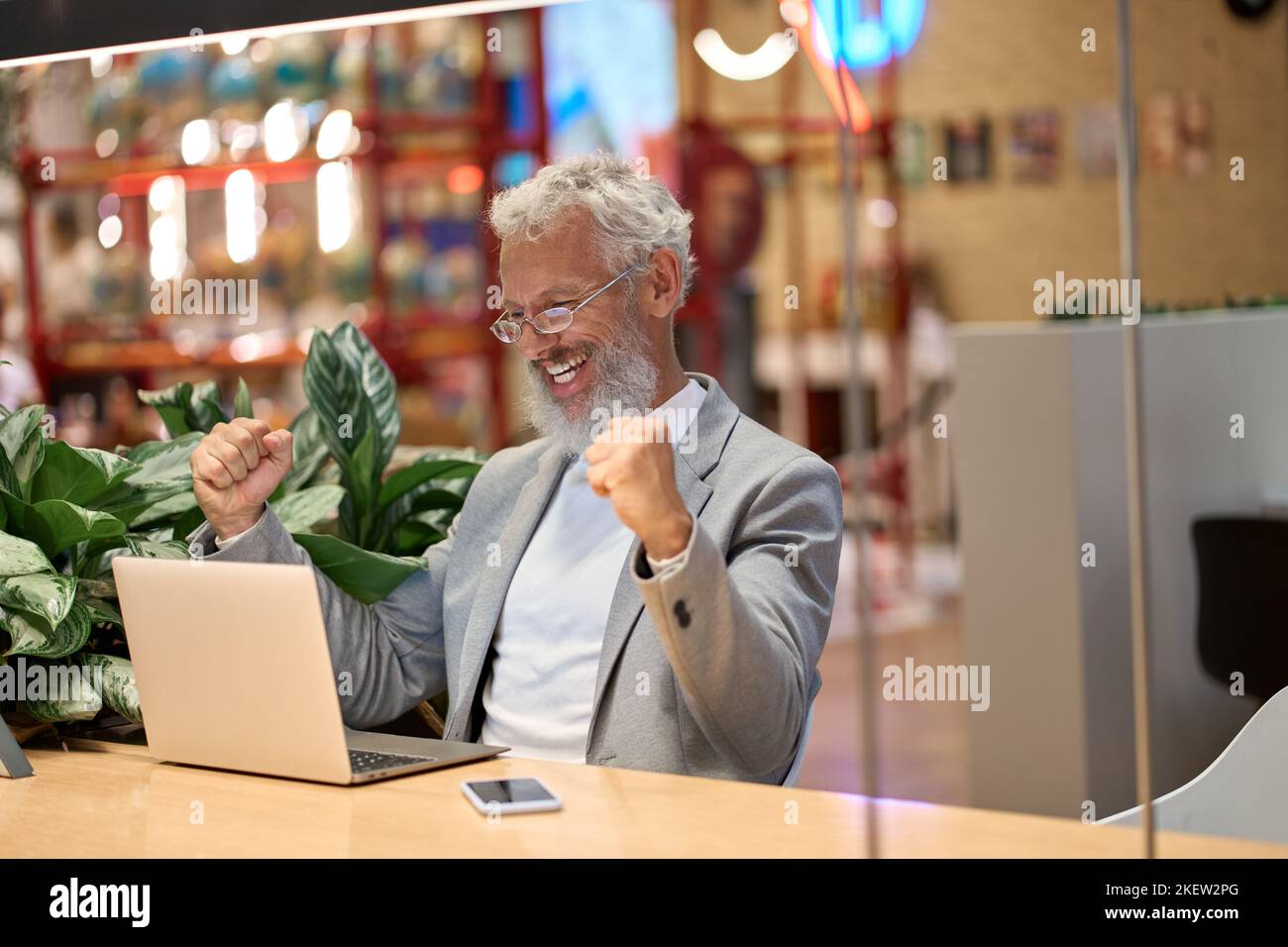 Bon vieux homme d'affaires regardant l'ordinateur portable célébrant Paris gagner en ligne. Banque D'Images