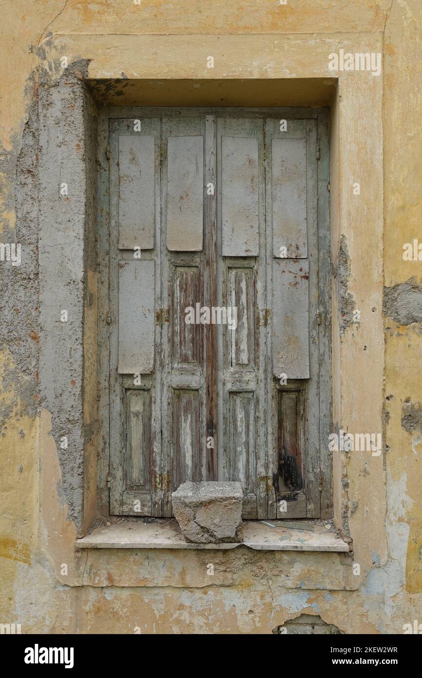 Ancienne fenêtre avec volet en bois et mur d'une maison abandonnée. Banque D'Images