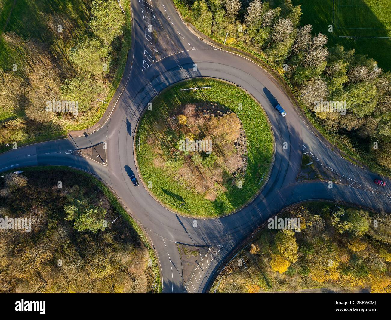 Vue aérienne d'un petit rond-point de circulation sur une route rurale avec des arbres colorés à l'automne. Banque D'Images