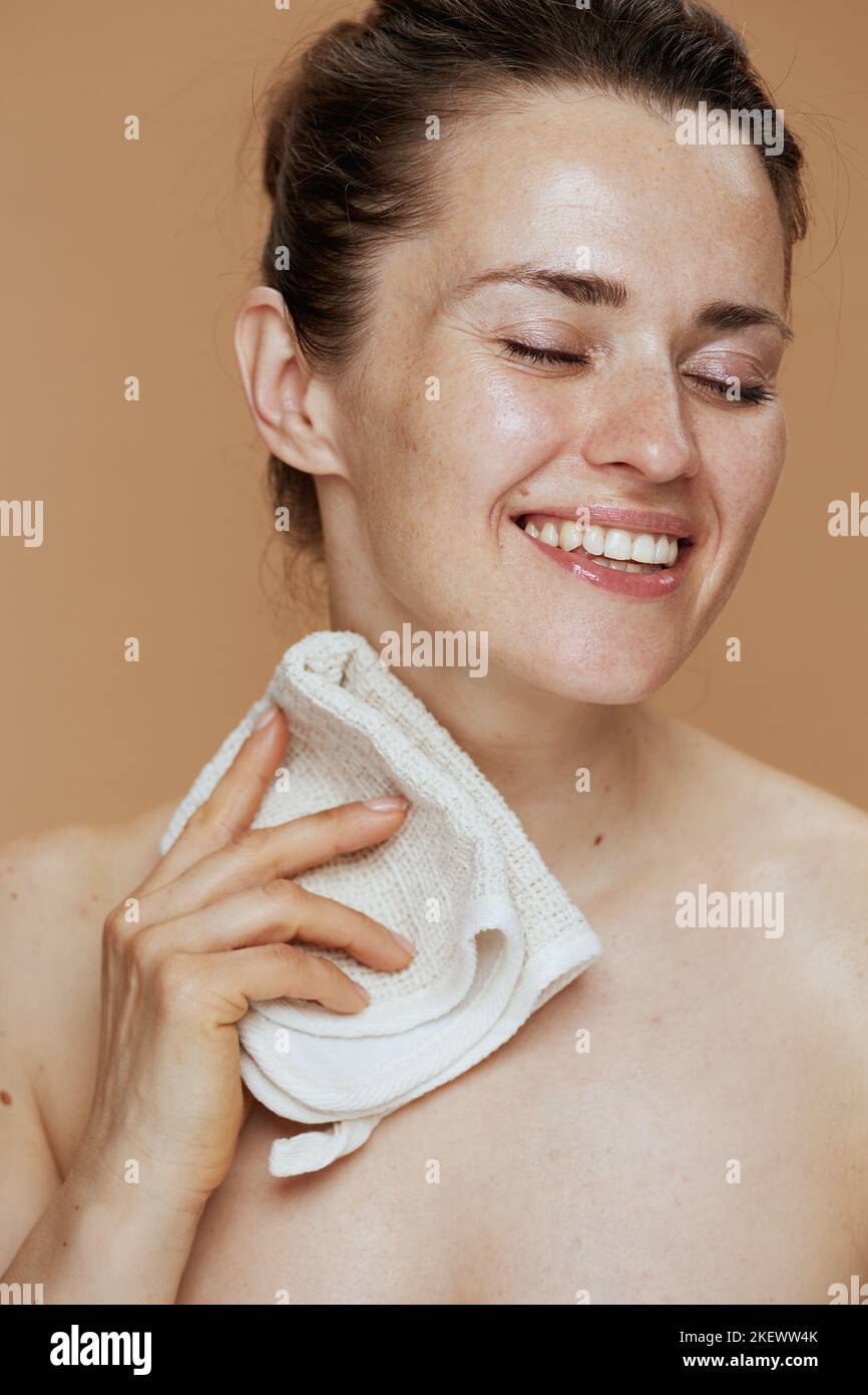 femme d'âge moyen souriante avec une serviette qui se lave le visage. Banque D'Images