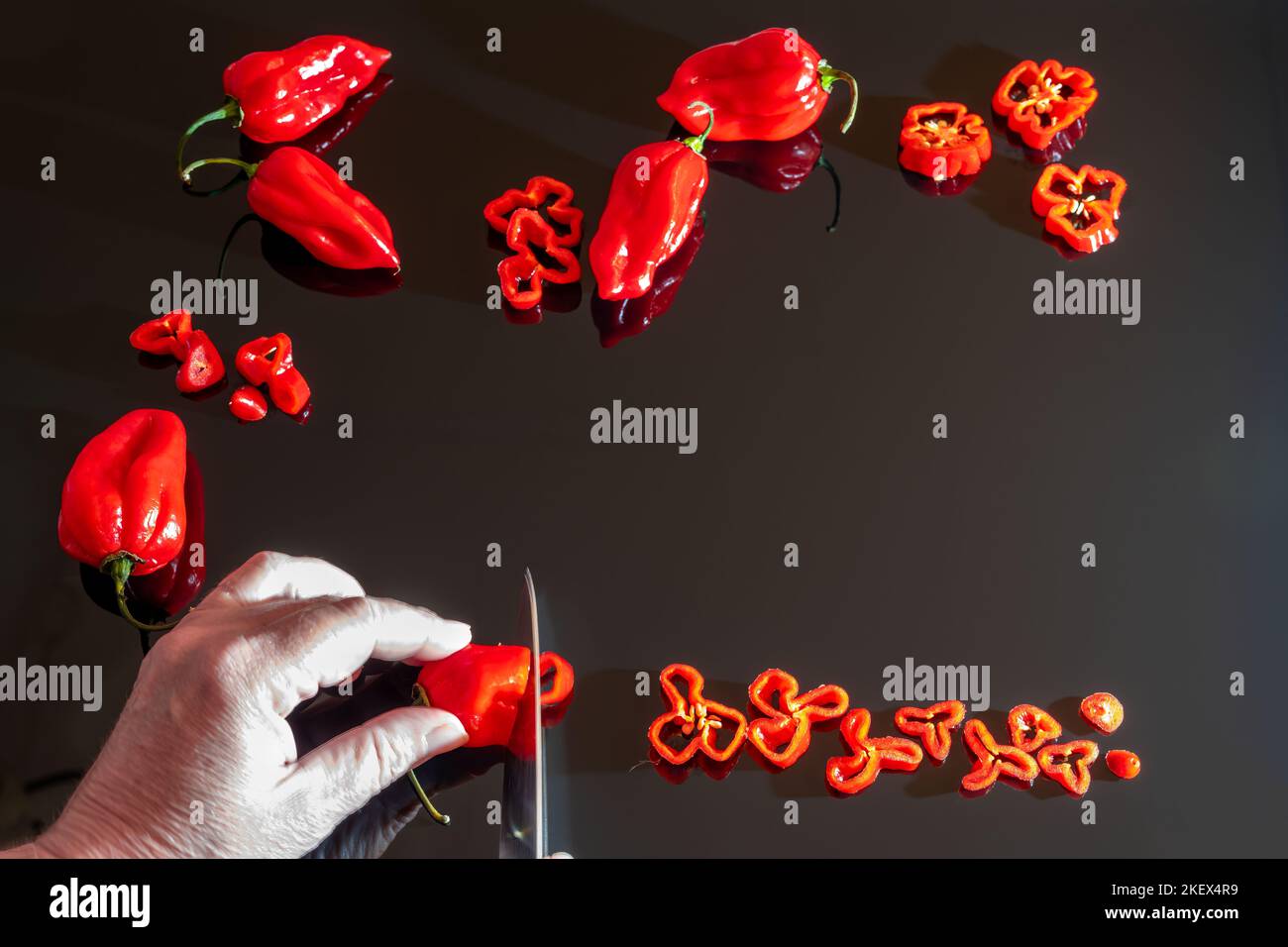 Capsicum chinense 'scotch Bonnet' est tranché sur une planche à découper noire Banque D'Images