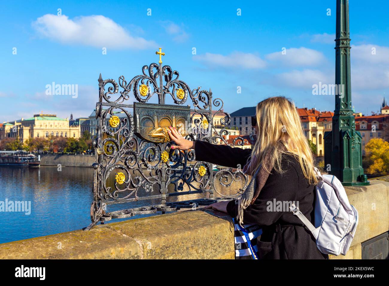 Touriste touchant un relief à l'endroit où Jean de Nepomuk s'est noyé dans la Vltava, Pont Charles, Prague, République Tchèque Banque D'Images Touriste touchant un relief à l'endroit où Jean de Nepomuk s'est noyé dans la Vltava, Pont Charles, Prague, République Tchèque Banque D'Images