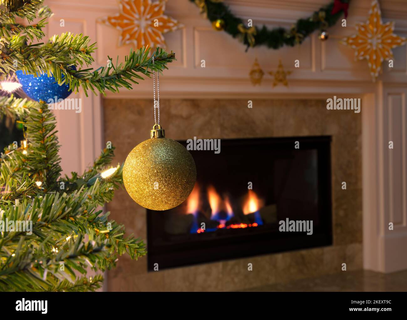 Gros plan d'un seul ornement de Noël doré suspendu d'un arbre avec foyer lumineux en arrière-plan Banque D'Images