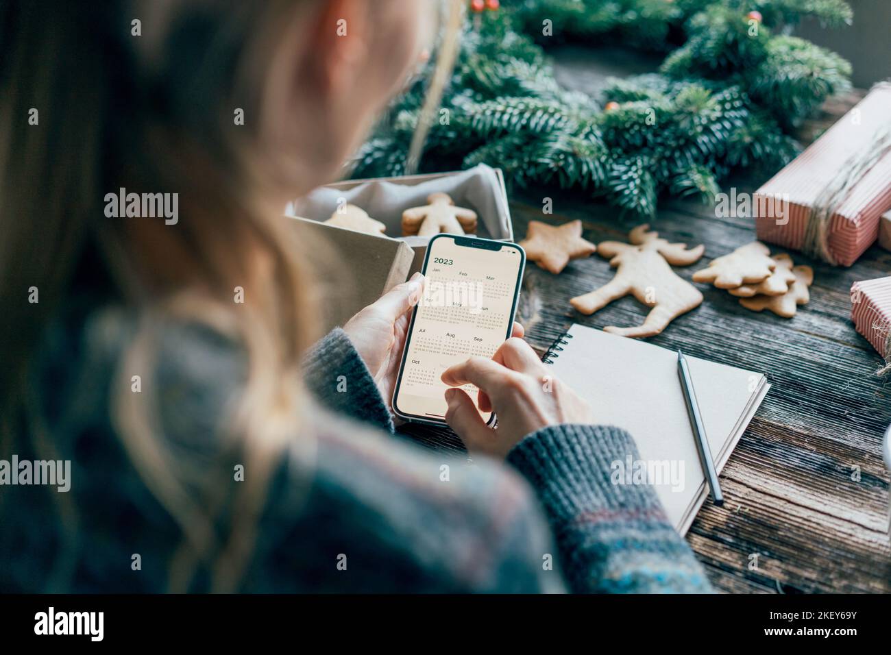 Femme prévoyant 2023 tenant un téléphone avec un calendrier à l'écran. Banque D'Images