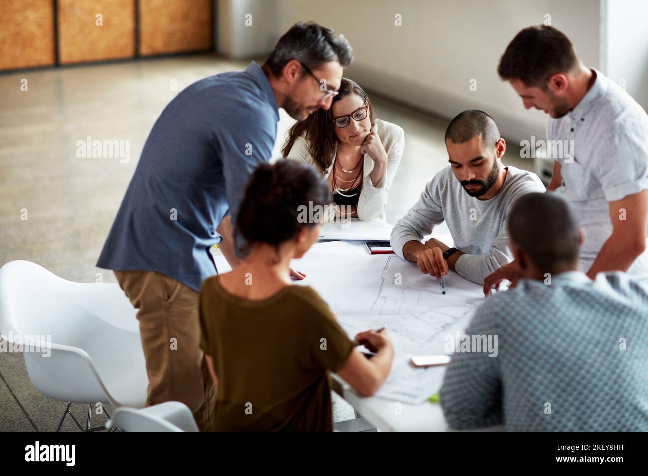 En regardant les plans, un groupe d'hommes d'affaires se réunit dans la salle de conférence. Banque D'Images