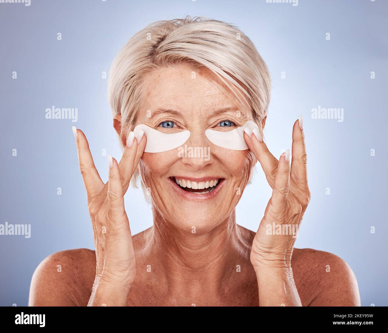 Visage, soin de la peau et vieux avec des cellules oculaires femme sur un fond bleu studio. Portrait, beauté et modèle de femme âgée du Canada avec anti-âge Banque D'Images