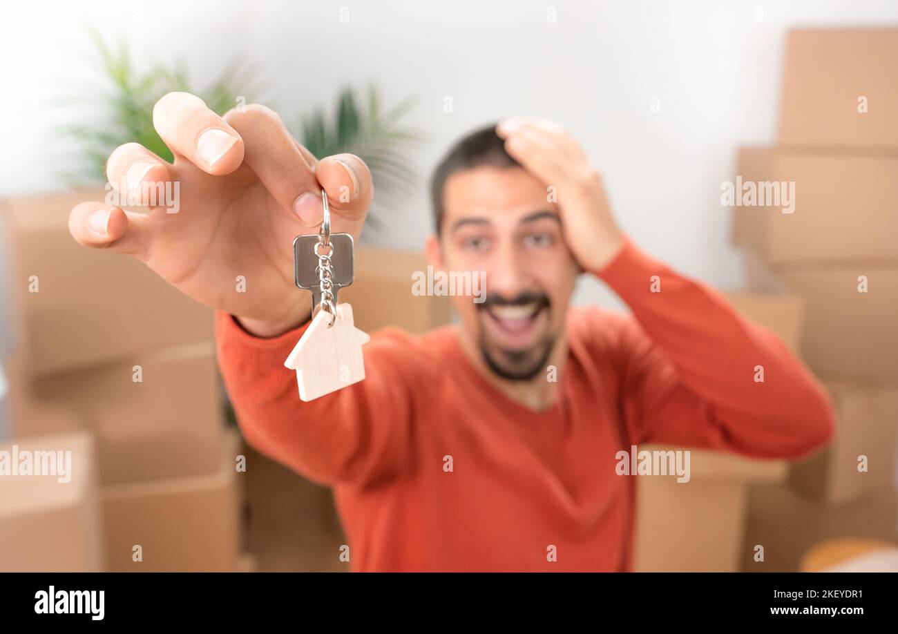 Joyeux jeune homme souriant avec le nouveau porte-clés de la maison en forme d'une maison en bois véritable état Banque D'Images