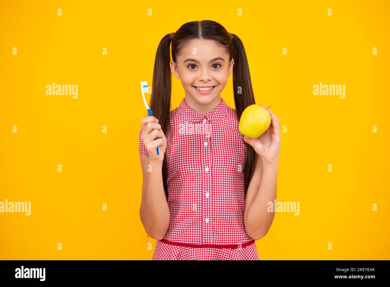 Portrait de la jeune fille caucasienne tient une brosse à dents se brossant ses dents, routine du matin, hygiène dentaire, isolé sur fond jaune. Joyeux adolescent Banque D'Images