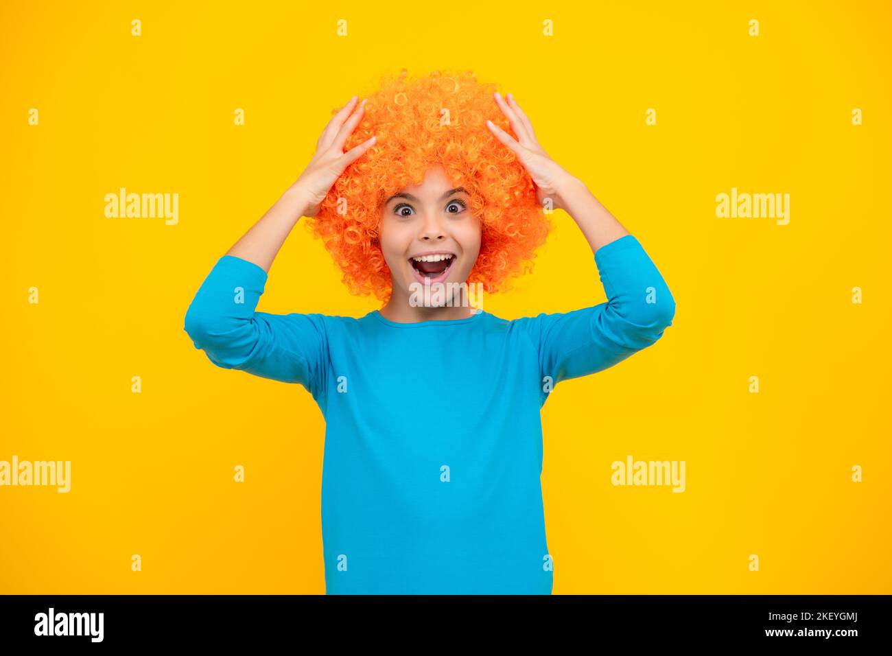 Fête d'anniversaire pour filles. Drôle d'enfant dans la perruque rouge curly. Temps de Amuse-toi bien. Jeune fille avec des cheveux orange, étant un clown. Adolescent excité, heureux étonné et Banque D'Images