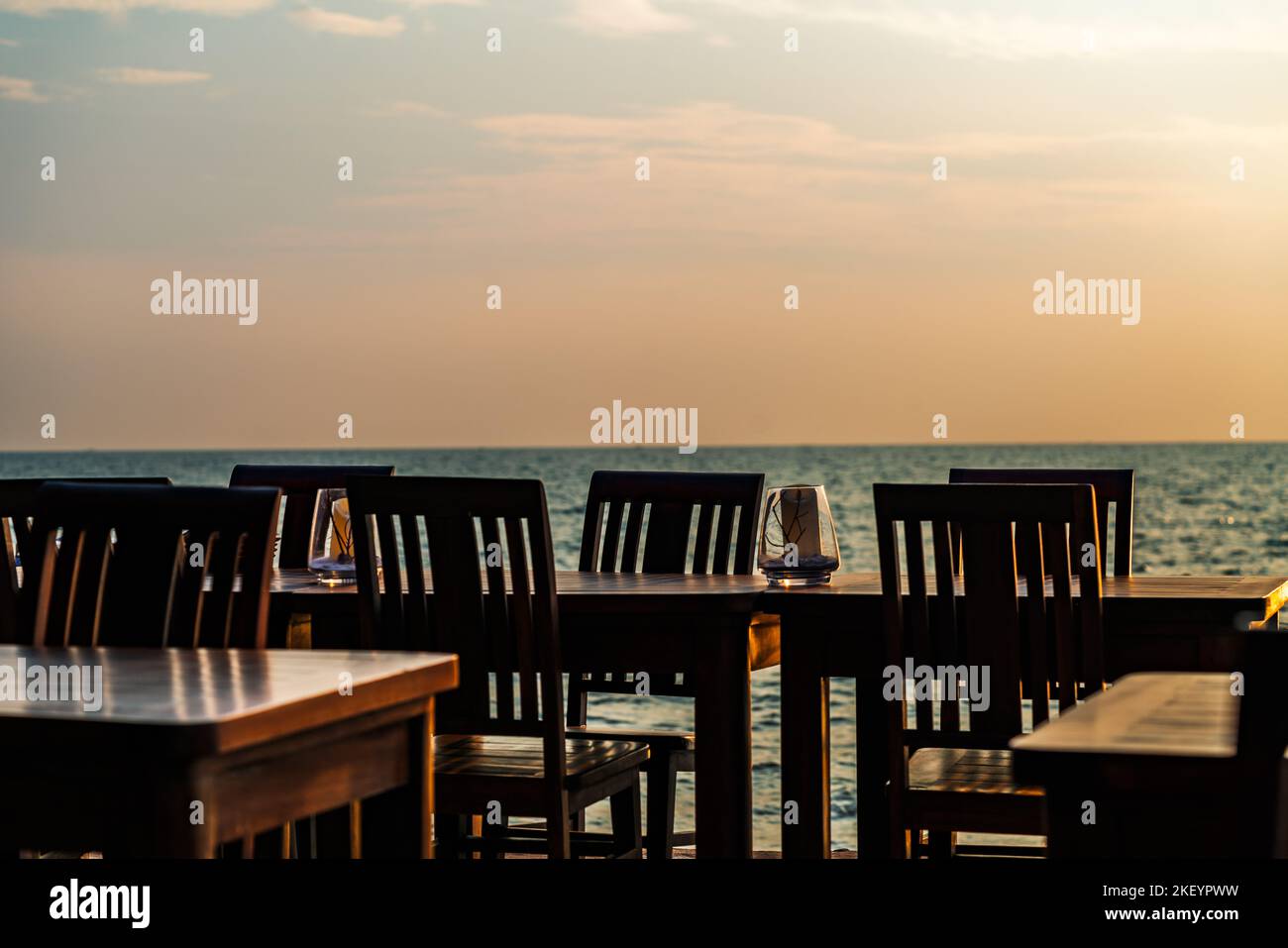 Rangée de tables et chaises en bois vintage d'un restaurant sur la plage de Thaïlande, pas de personnes, heure du coucher du soleil, fond flou de la mer et du ciel. Spa vierge Banque D'Images