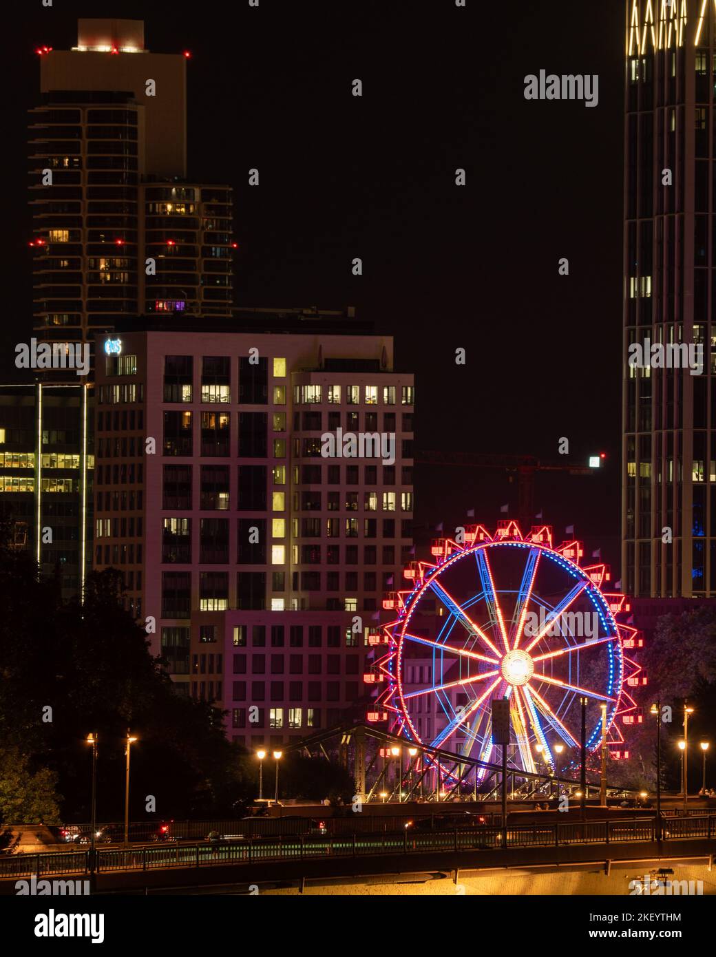 Une verticale de la ville de Francfort la nuit et la grande roue qui brillent devant les bâtiments Banque D'Images