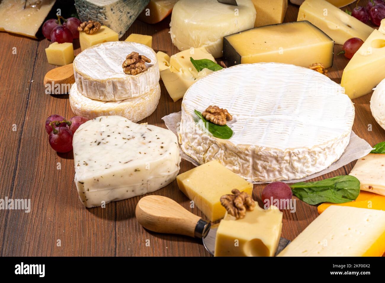 Différentes sortes de fromages. Plateau de fromages avec divers fromages, avec des raisins, des noix, un couteau à fromage et des épices, un espace de copie en bois Banque D'Images
