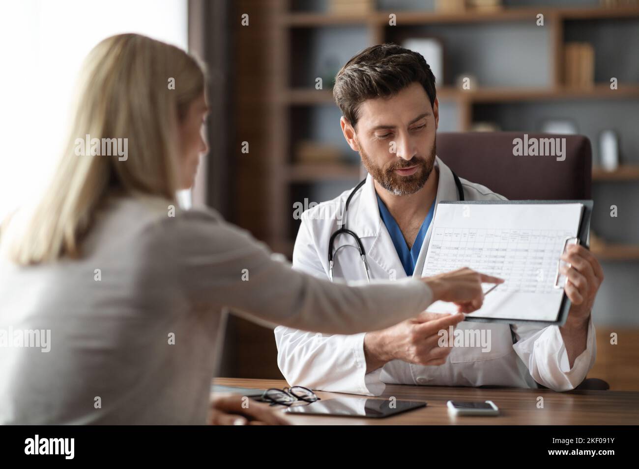 Médecin de sexe masculin montrant les résultats des tests médicaux au patient de sexe féminin en clinique Banque D'Images