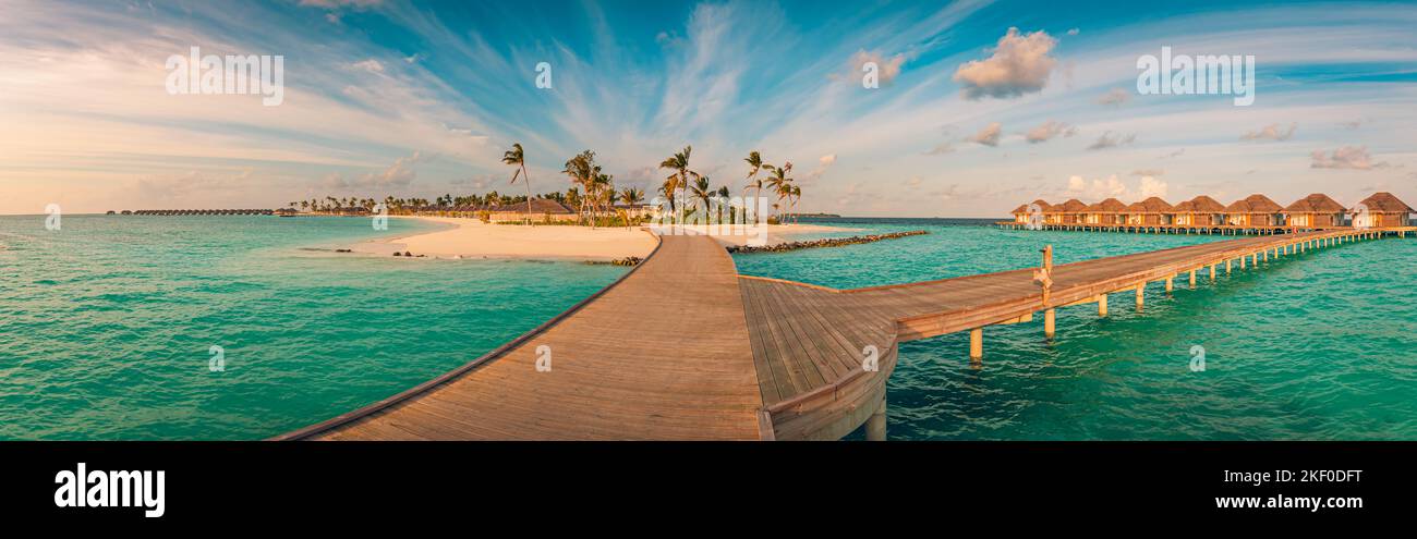 Magnifique panorama au coucher du soleil aux Maldives. Complexe de luxe villas paysage marin avec pont en bois sous ciel nuageux coloré. Paysage fantastique des hôtels de voyage Banque D'Images
