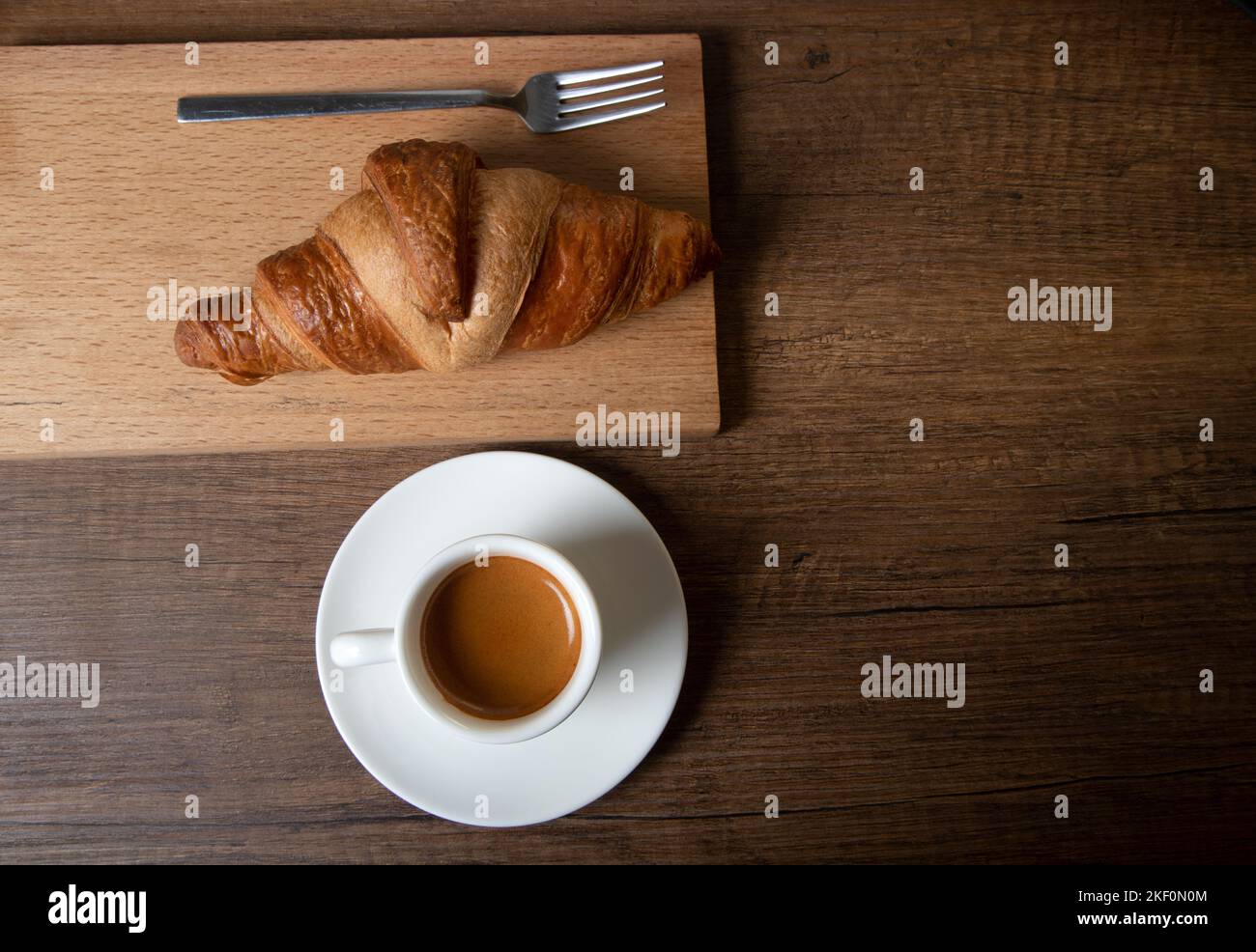 Croissant avec espresso dans une tasse blanche sur une table en bois Banque D'Images