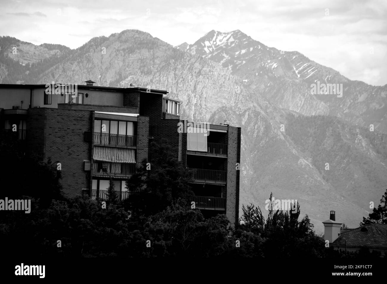 Une photo en échelle de gris d'un bâtiment résidentiel contre des montagnes Banque D'Images