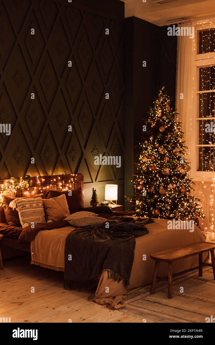 Chambre sombre avec décorations de Noël. Grand lit et arbre de Noël Banque D'Images