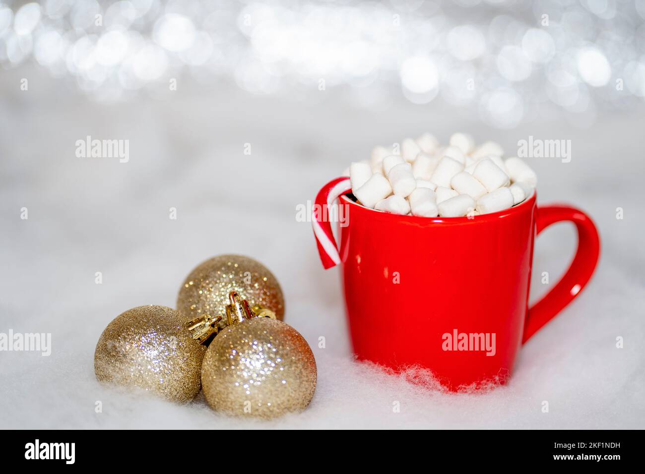 Tasse rouge avec chocolat chaud et guimauve avec décorations de Noël dorées Banque D'Images