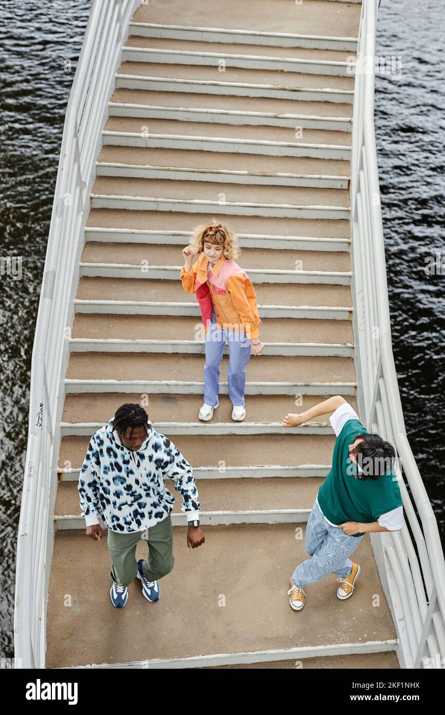 Vue graphique du dessus de groupe de jeunes dansant sur les escaliers à l'extérieur et portant des vêtements colorés de style de rue Banque D'Images