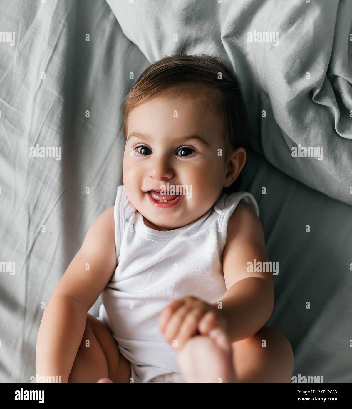 Beau sourire mignon bébé. Portrait en gros plan de bébé couché heureux regardant l'appareil photo Banque D'Images