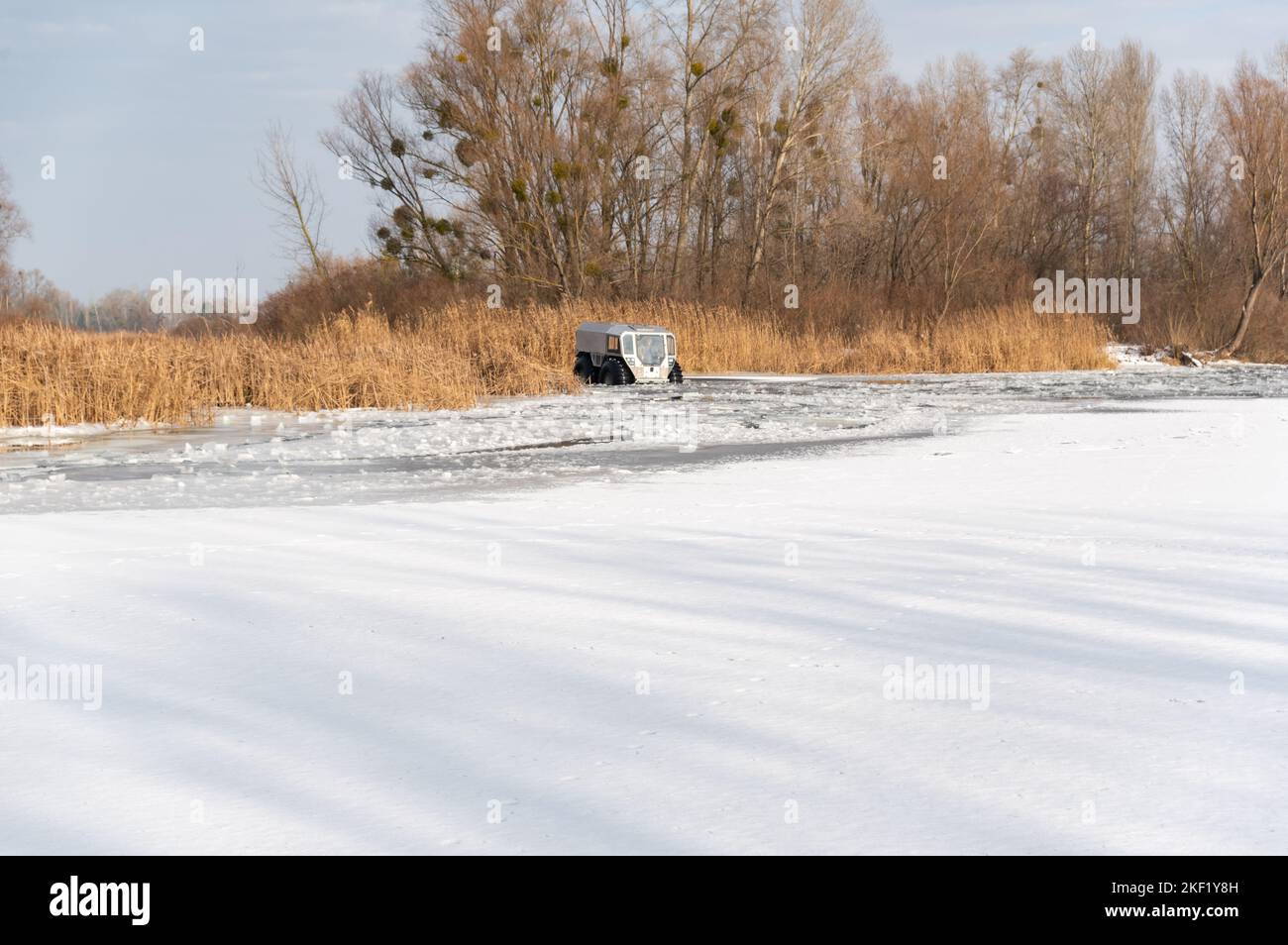 Transport traversant les rivières. Une voiture avec de grandes roues traversant la rivière. 4x4 sur la rivière en hiver. Banque D'Images