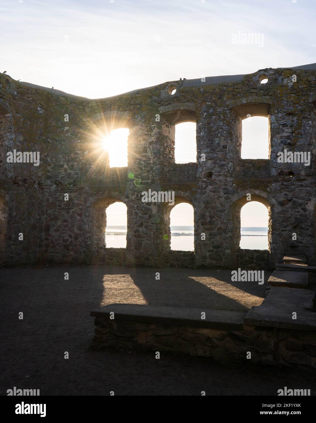 Un soleil qui brille à travers l'une des six fenêtres sur un mur du château de Brahehus en ruines et une vue sur la mer calme et le ciel clair Banque D'Images