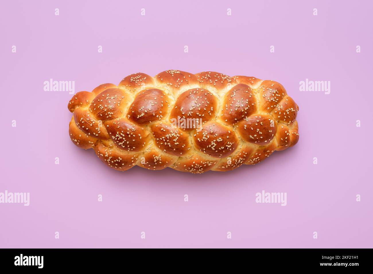 Directement au-dessus de la vue avec un pain de challah maison minimaliste sur une table pourpre. Pain tressé, une recette juive traditionnelle, sur un dos coloré Banque D'Images