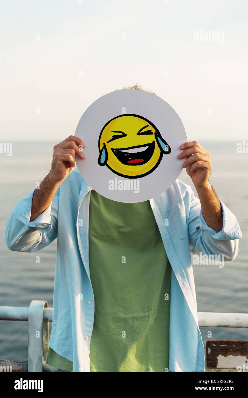 Guy cachant son visage avec une main riant le réseau social emoji riant avec des larmes - les gens et le monde numérique dans la vraie vie concept Banque D'Images