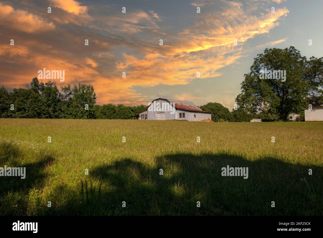 belle ancienne grange avec un toit en étain rouillé sur une ferme tandis que les tempêtes se déplacent dans un jour d'été Banque D'Images