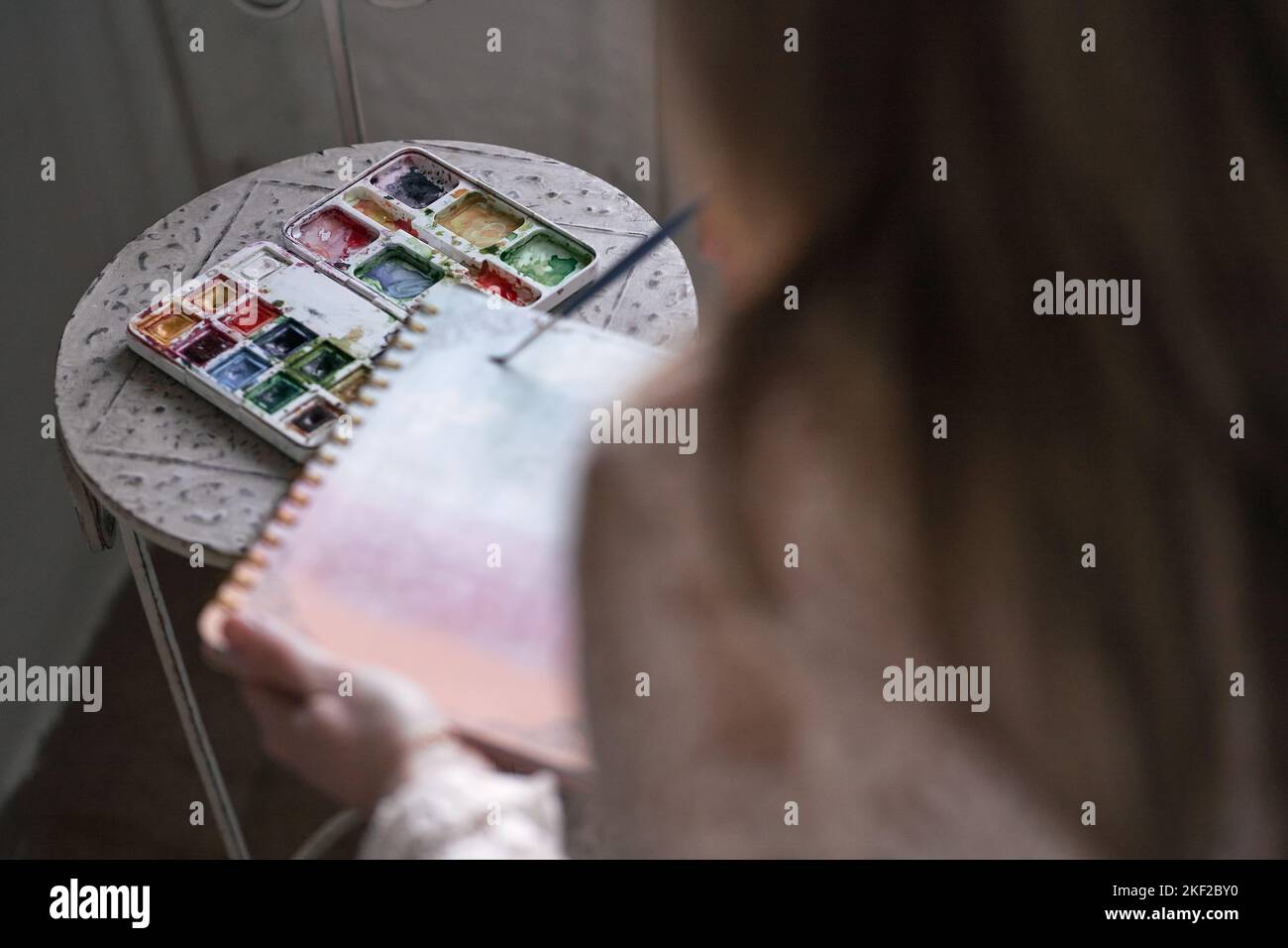 gros plan de la main gauche d'une femme tenant un cahier à anneaux et une brosse glissant dessus Banque D'Images
