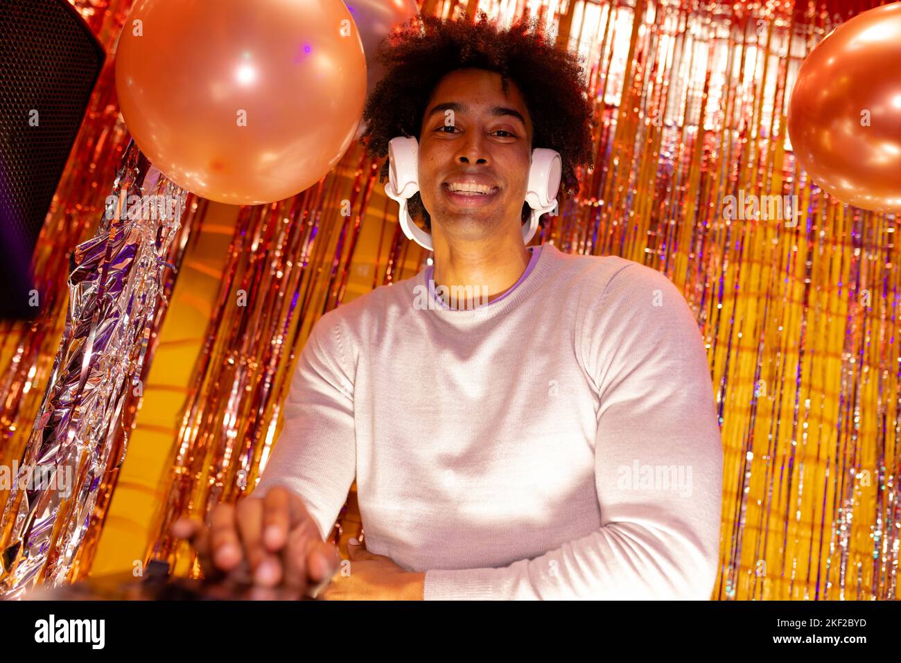 Portrait d'un DJ afro-américain souriant dans un casque jouant de la musique dans une boîte de nuit Banque D'Images