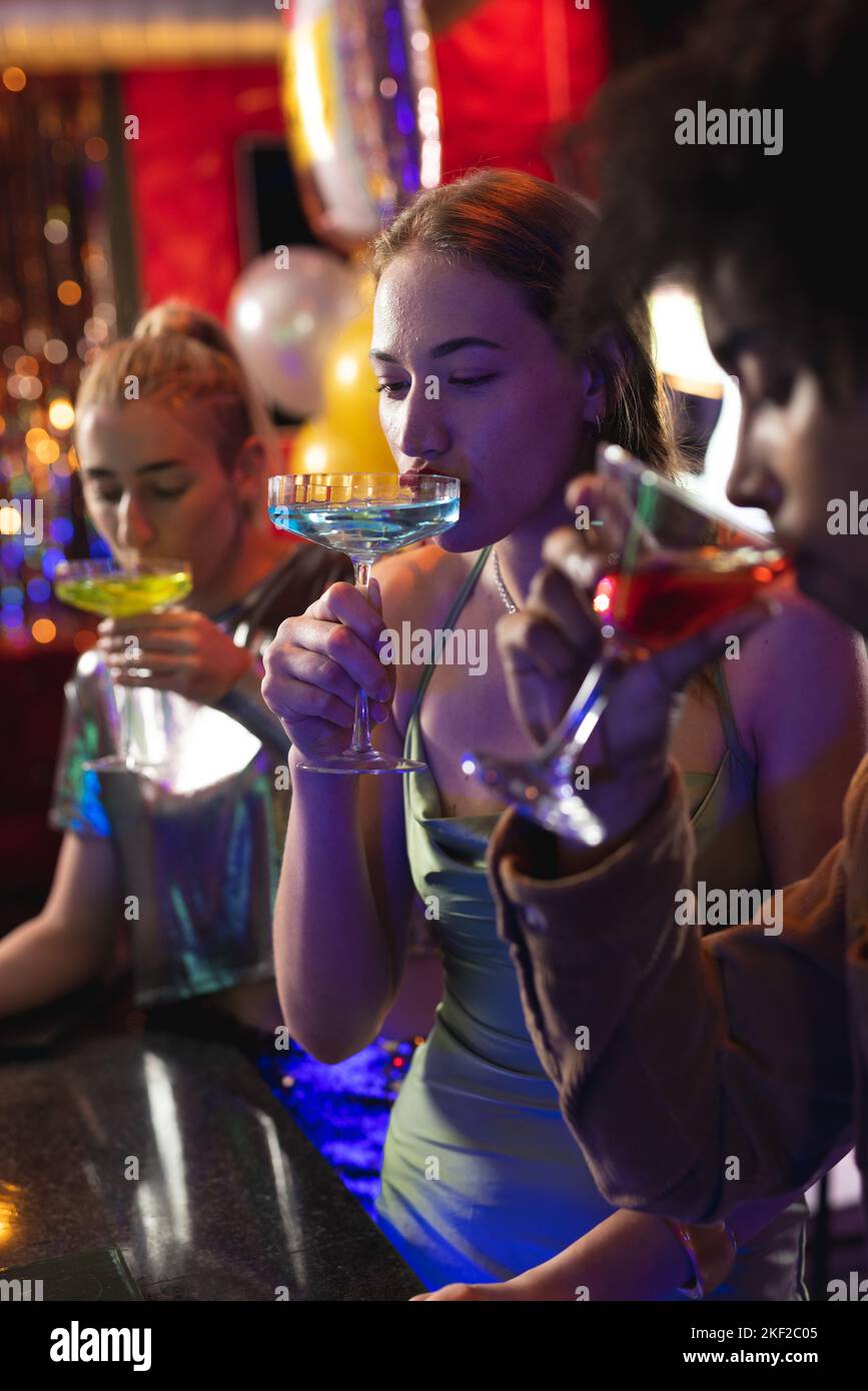 Trois amis hommes et femmes heureux et variés sirotant des cocktails au bar de la discothèque Banque D'Images