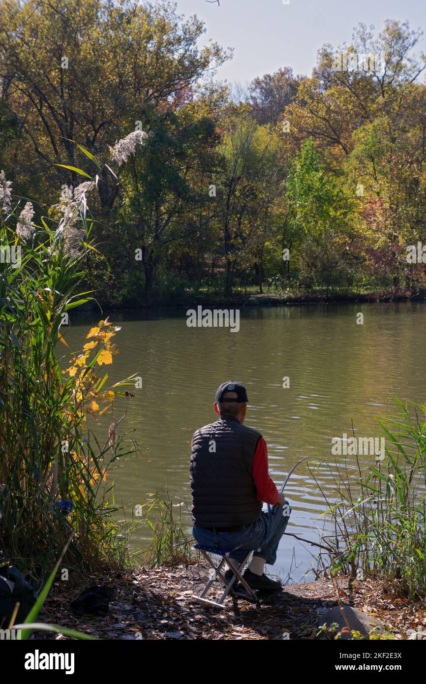 Un homme non identifié pêche au lac dans le parc Kissena à Queens, New York Banque D'Images