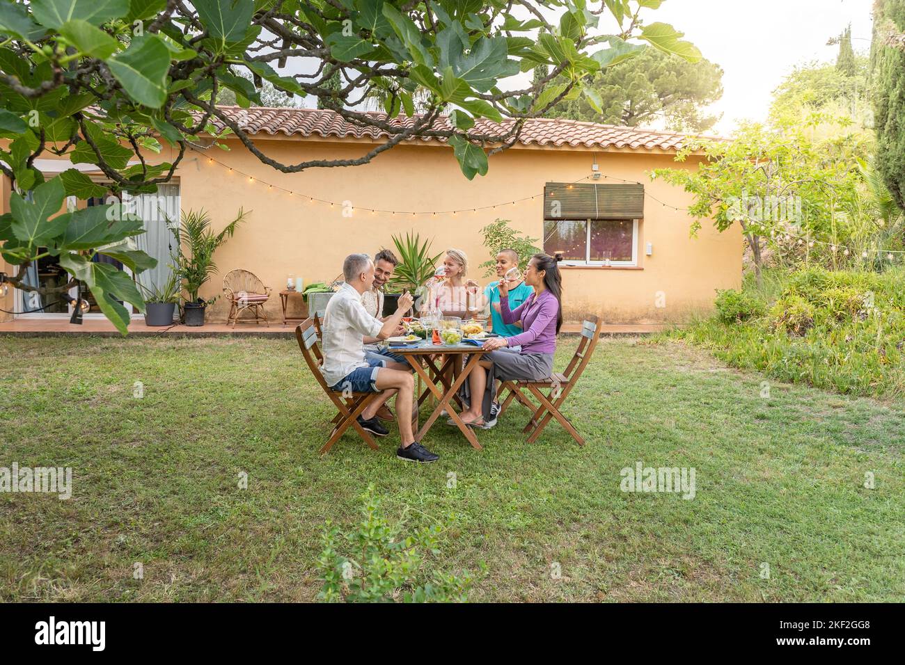 Photo d'amis mangeant et buvant dans le patio. Personnes d'âge moyen et gaies autour de la table. Banque D'Images