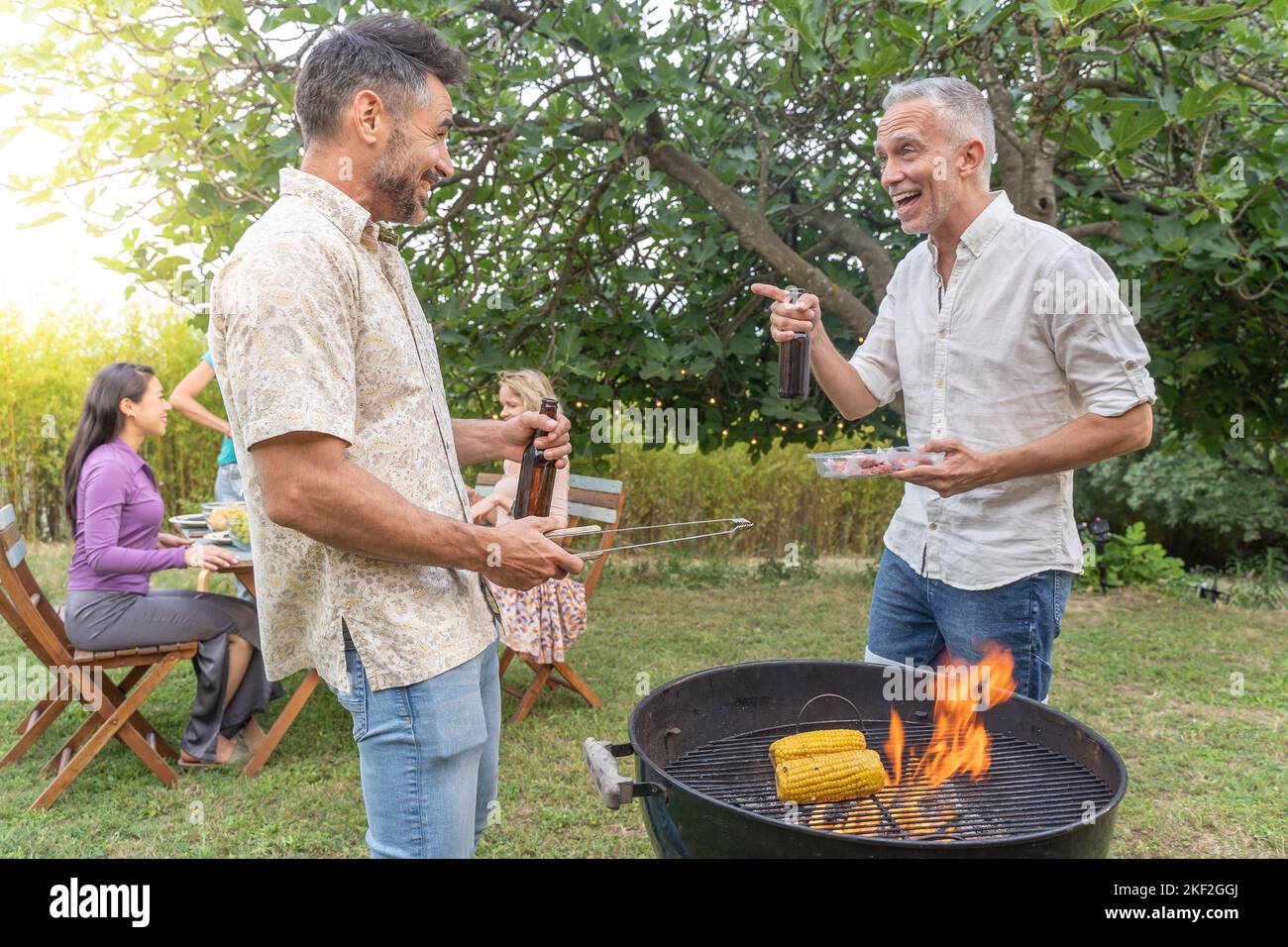 Amis multiethniques d'âge moyen autour du barbecue souriant heureux et riant ensemble. Concept de joie. Banque D'Images