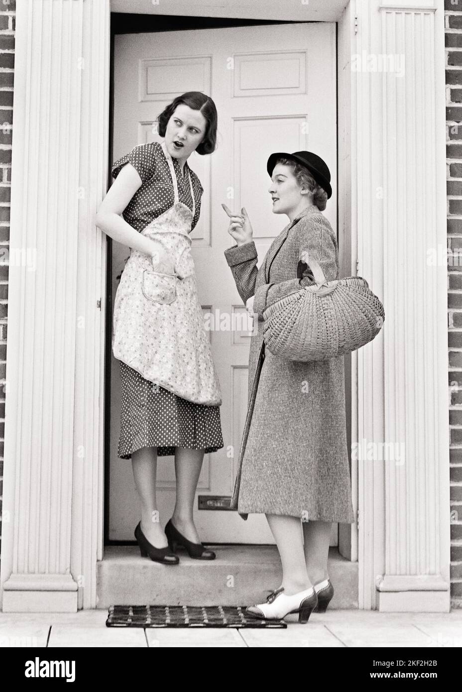 1930S DEUX FEMMES PARLANT DANS LA PORTE POUR LA MAISON UNE DANS LE CHAPEAU ET LE MANTEAU PORTANT LE PANIER DEMANDANT DES INSTRUCTIONS DE LA FEMME AU FOYER PORTANT TABLIER - S8290 HAR001 FEMMES SEA ACCUEIL VIE COPIE ESPACE FEMMES PLEINE LONGUEUR DEMANDE AUX PERSONNES DIRECTIONS B&W FOYER DIRECTION EXTÉRIEURE DANS À LA MAISON VISITE CONCEPTUELLE CONVERSING ÂGE ADULTE MOYEN-ADULTE MOYENNE-ADULTE JEUNE FEMME ADULTE NOIR ET BLANC RACE BLANCHE HAR001 OLD FASHIONED Banque D'Images