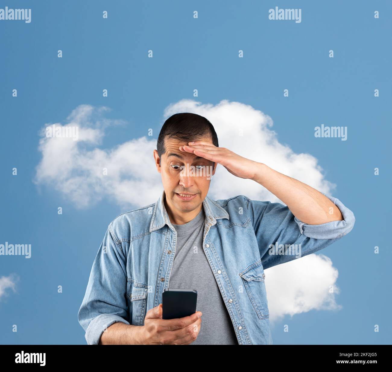Homme envoyant des SMS avec un smartphone sur un fond de nuage isolé stressé de main en tête, choqué par la honte et le visage surprise, en colère et frustré. FE Banque D'Images
