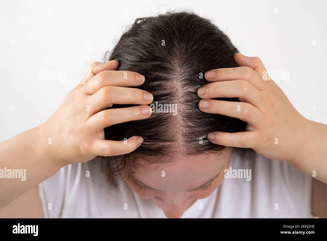 Gros plan de la femme contrôle la perte de cheveux et peu de volume avec les cheveux fins sur un fond blanc à cause du soleil Banque D'Images