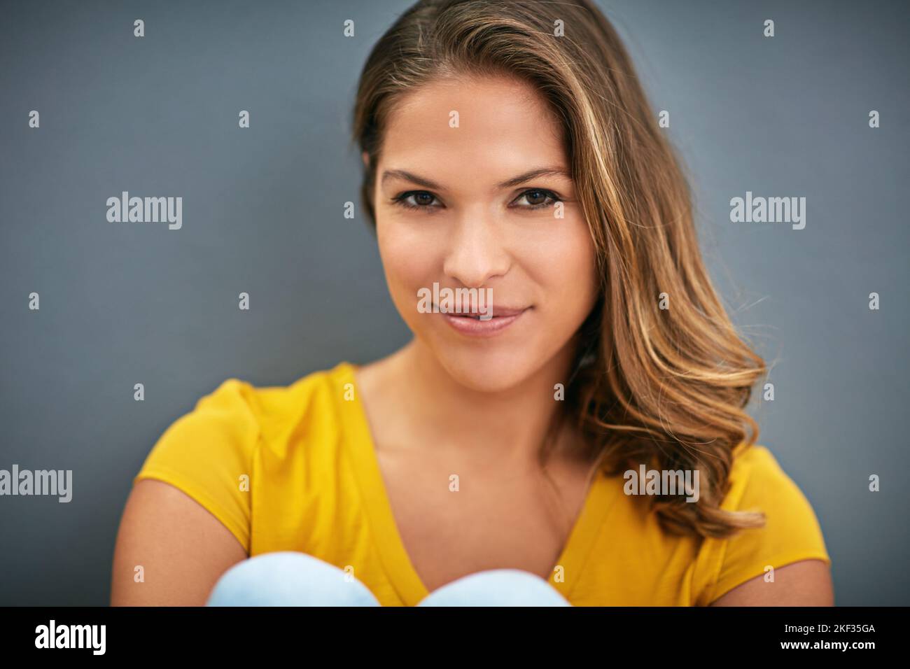 Pleine de confiance. Une jeune femme posant contre un mur gris. Banque D'Images